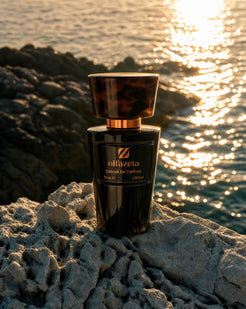 Black Olfazeta by Chogan Millésime bottle, tortoiseshell cap, on pale rocks facing the shimmering sea