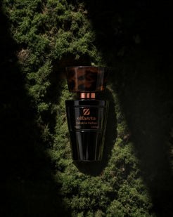 Black bottle Olfazeta by Chogan Millésime N°61 with a tortoiseshell cap, resting on a bed of green moss