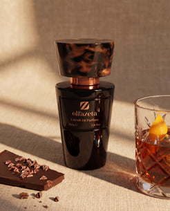 Black bottle Olfazeta by Chogan Millésime N°30 on linen, dark chocolate and a glass of whisky with orange zest